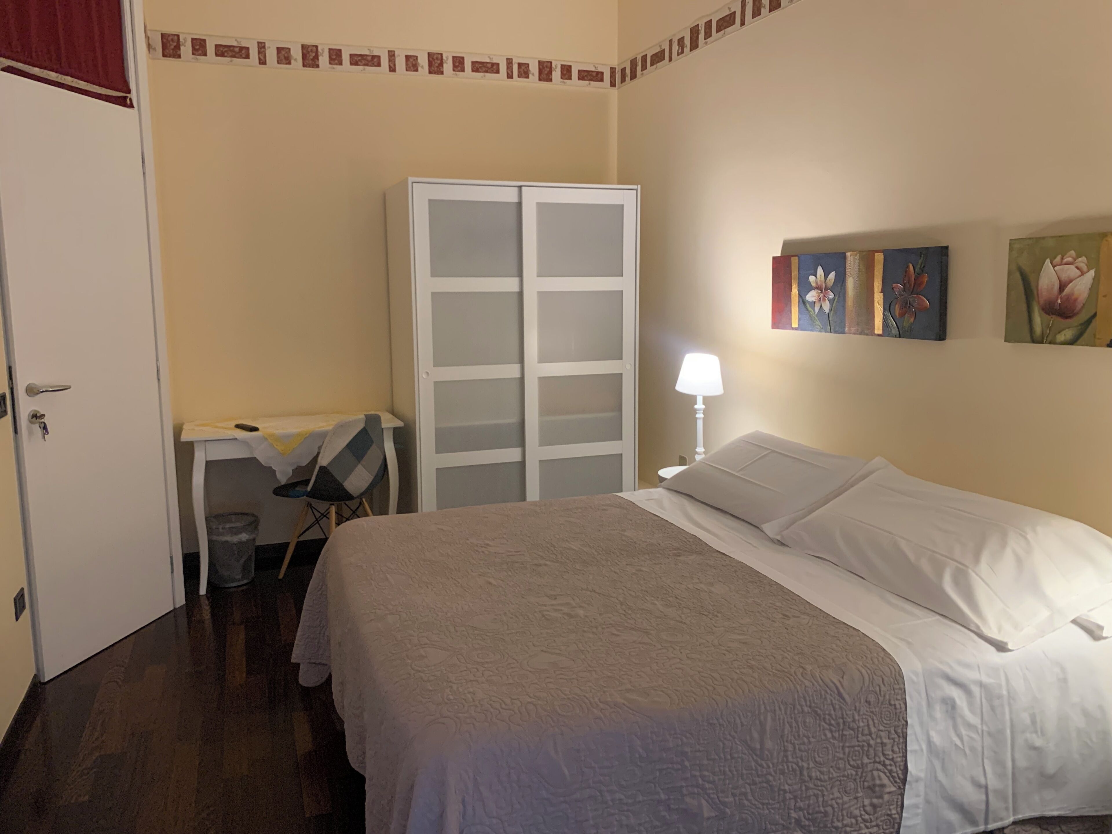 Un dormitorio con cama, escritorio, armario y un cubo de basura.