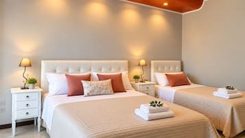 Habitación de hotel con dos camas, cada una con cabecera, mesitas de noche, lámparas y toallas dobladas.