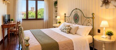 Habitación de hotel con una cama grande, un escritorio con una silla, un televisor y vistas a una torre por la ventana.