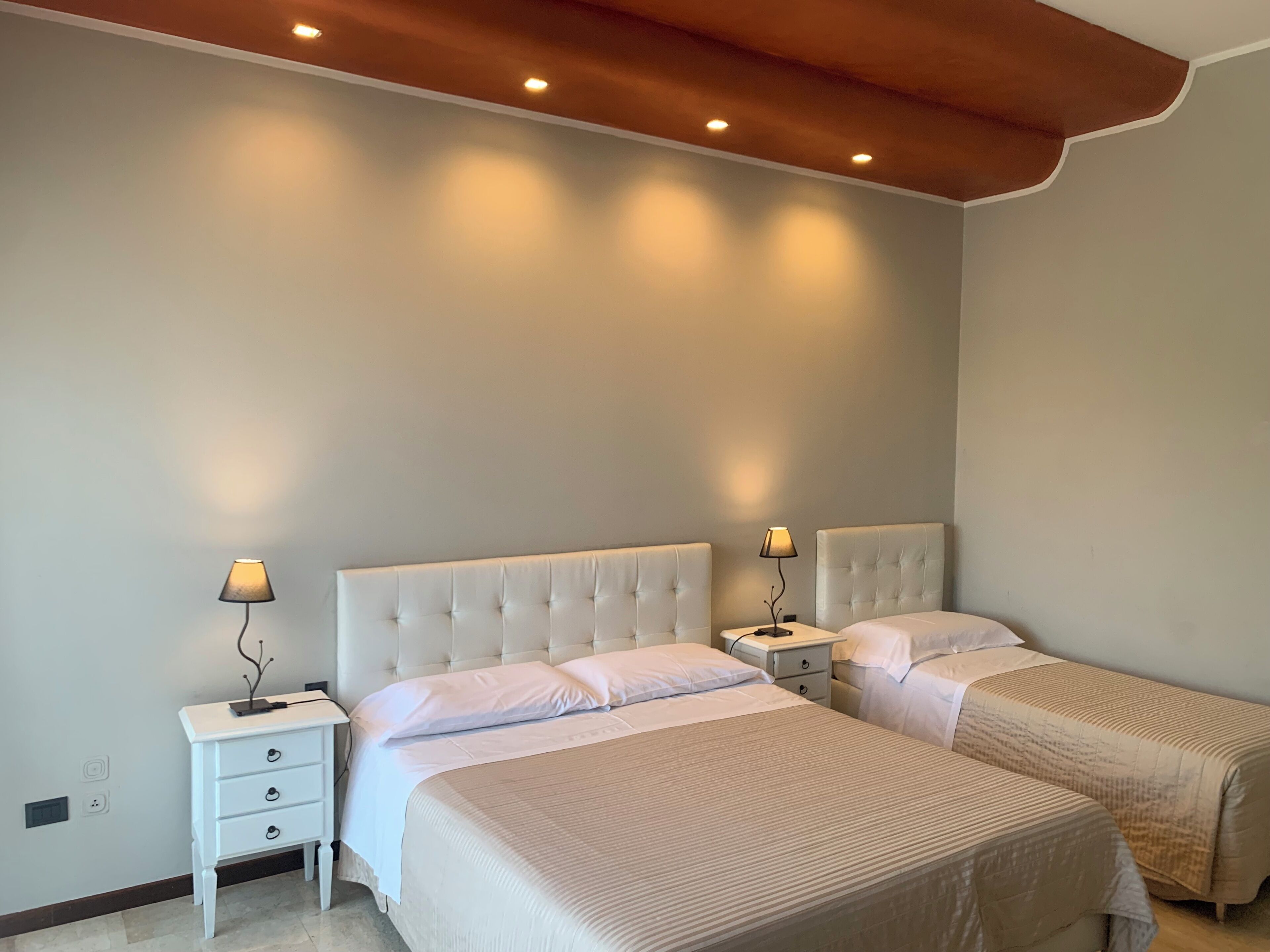 A bedroom with two beds, a white dresser, and a nightstand with lamps.