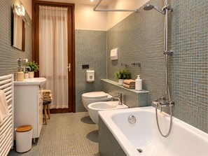 A bathroom with a bathtub, toilet, sink, and shower. - Casamore Rooms (Verona)
