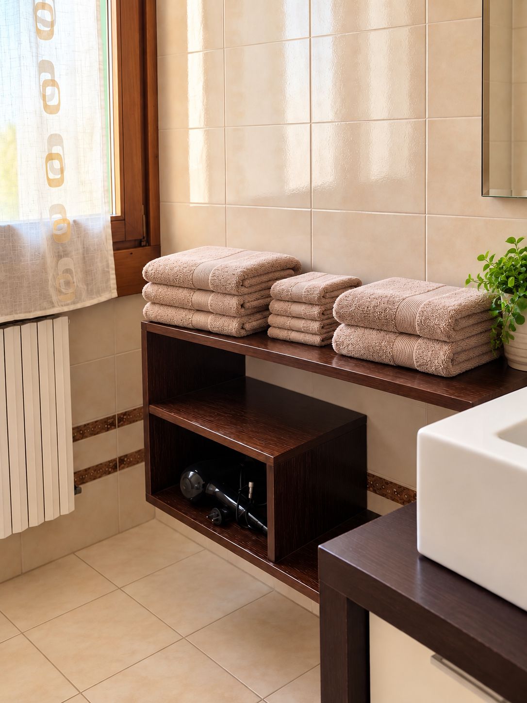 A bathroom with a wooden shelf holding folded towels, a radiator, and a potted plant.