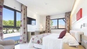 Habitación de hotel con cama, escritorio, silla, teléfono y televisión.