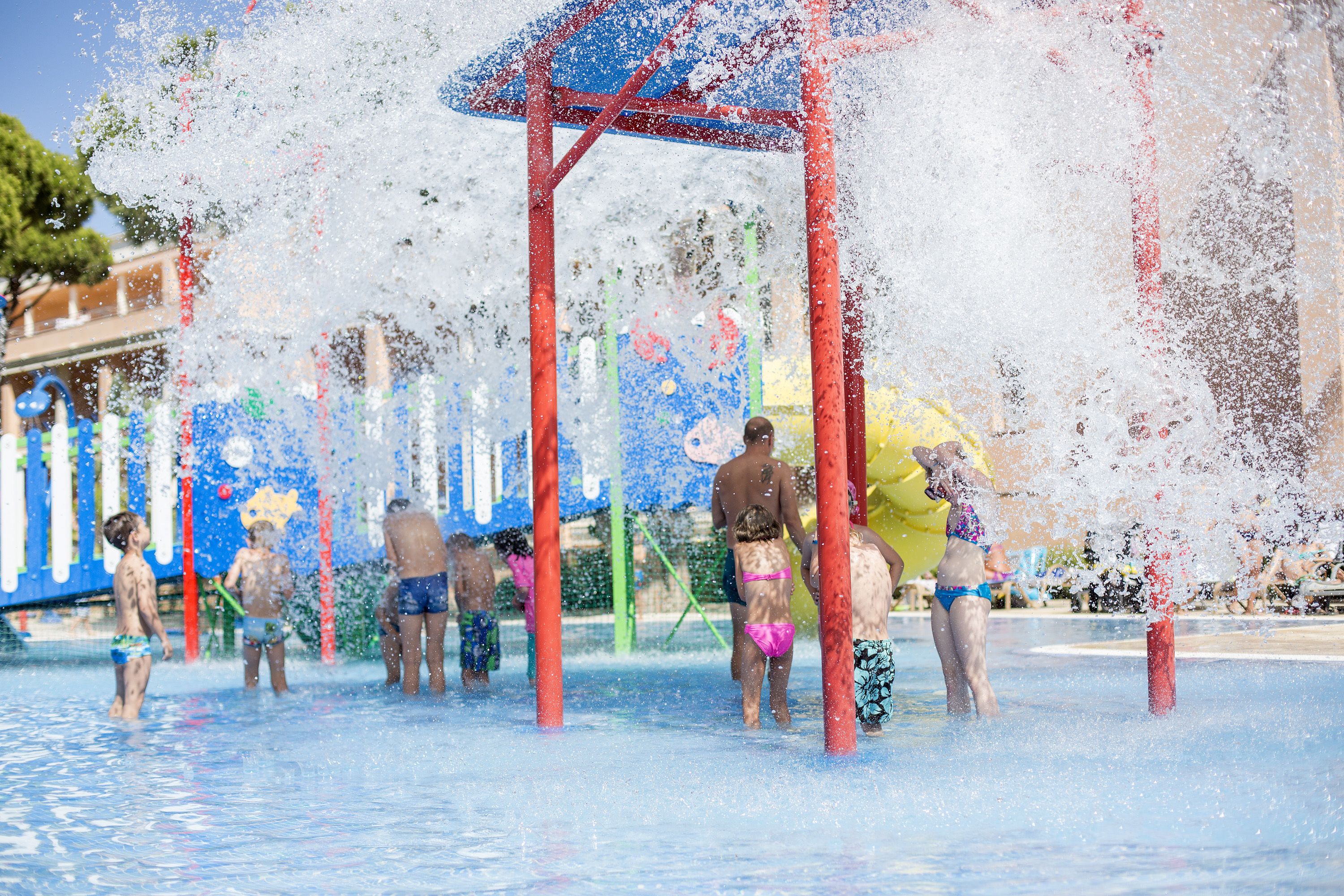 A water play area with multiple children and adults.