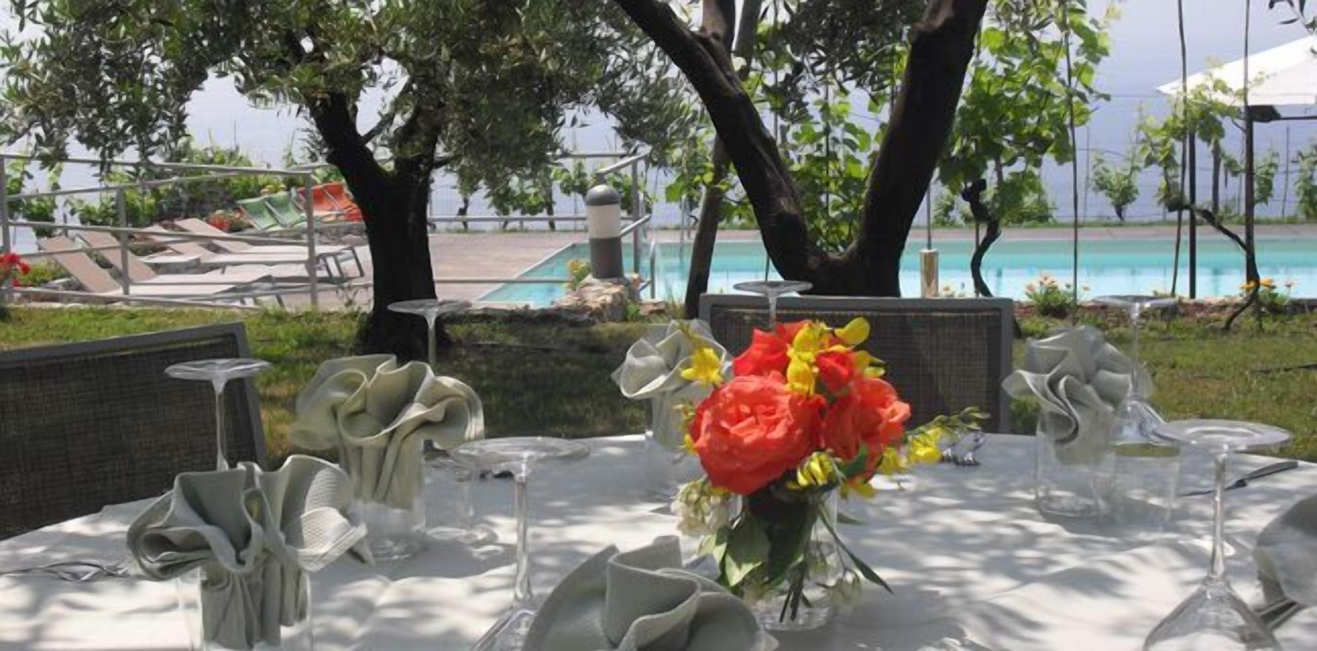 An outdoor dining area with tables set for a meal, overlooking a pool.