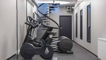 Un gimnasio con máquinas de cardio y una escalera.