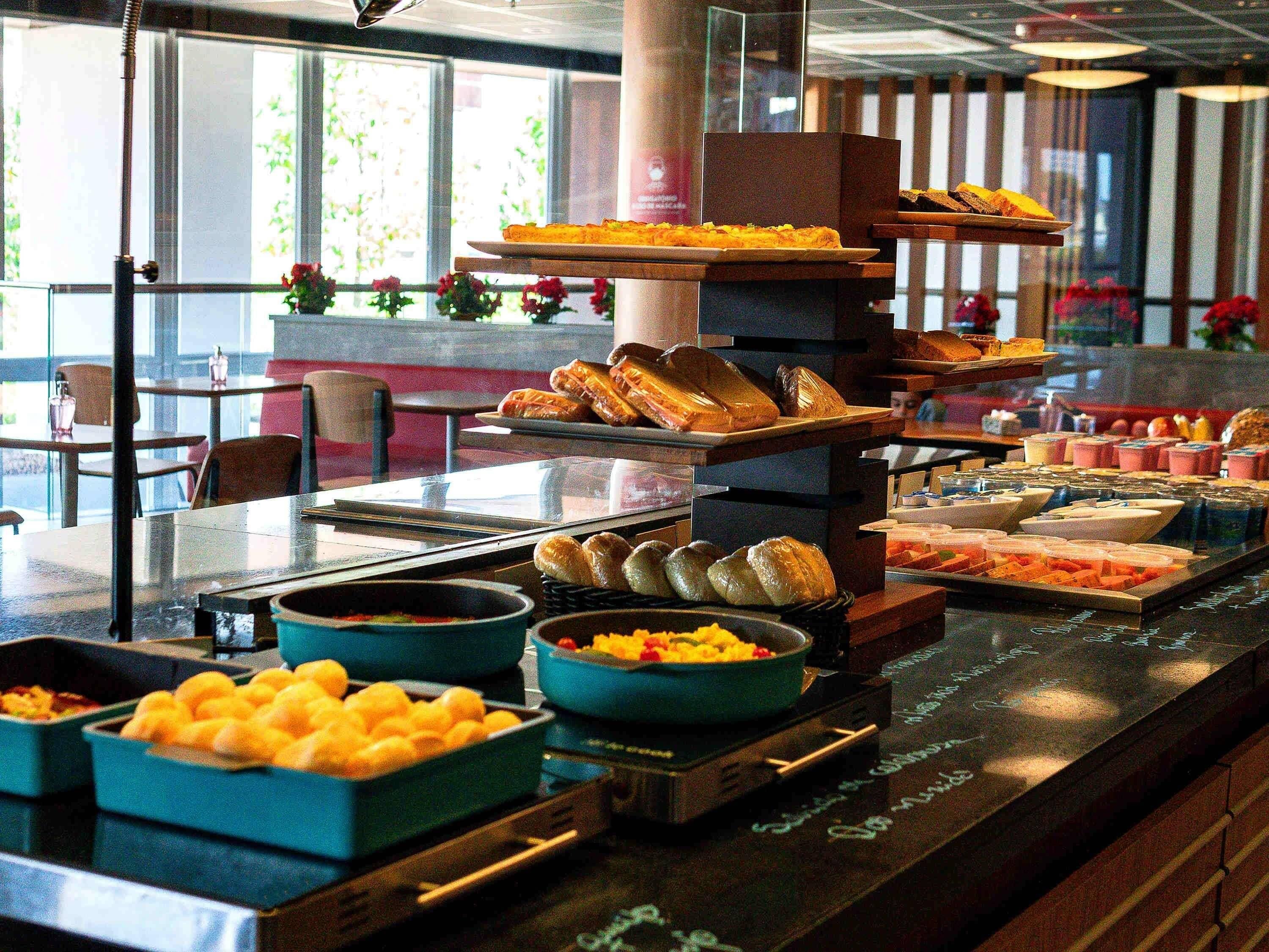 A buffet with various food items and a seating area with tables and chairs.