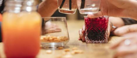 Un grupo de personas sosteniendo vasos con pajitas, un tarro con líquido anaranjado y un vaso con líquido rojo.