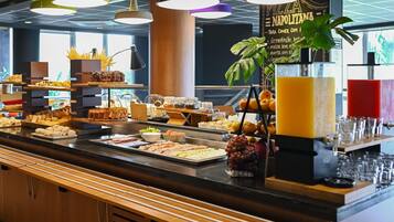 Buffet com diversos alimentos e um dispensador de sucos.