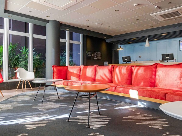 Relax in the stylish waiting area with a vibrant sofa, a chair, and a small table.