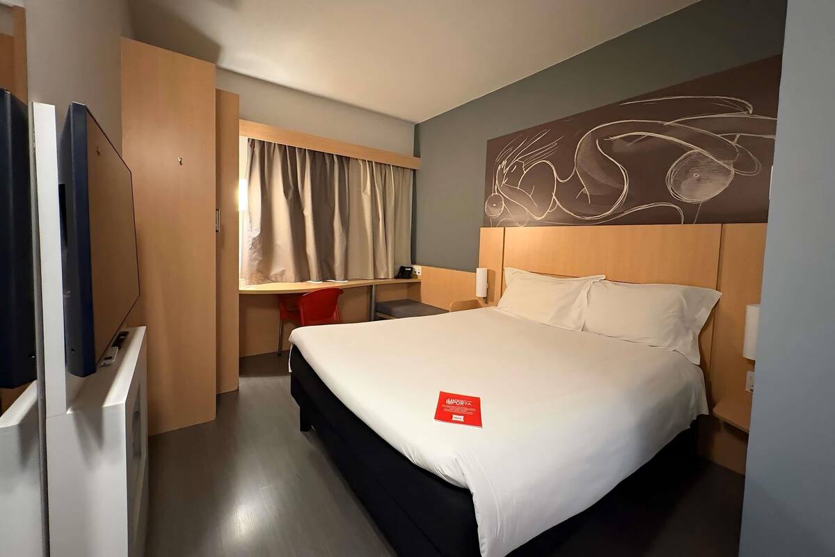 Een hotelkamer met een bed, bureau, stoel en televisie.
