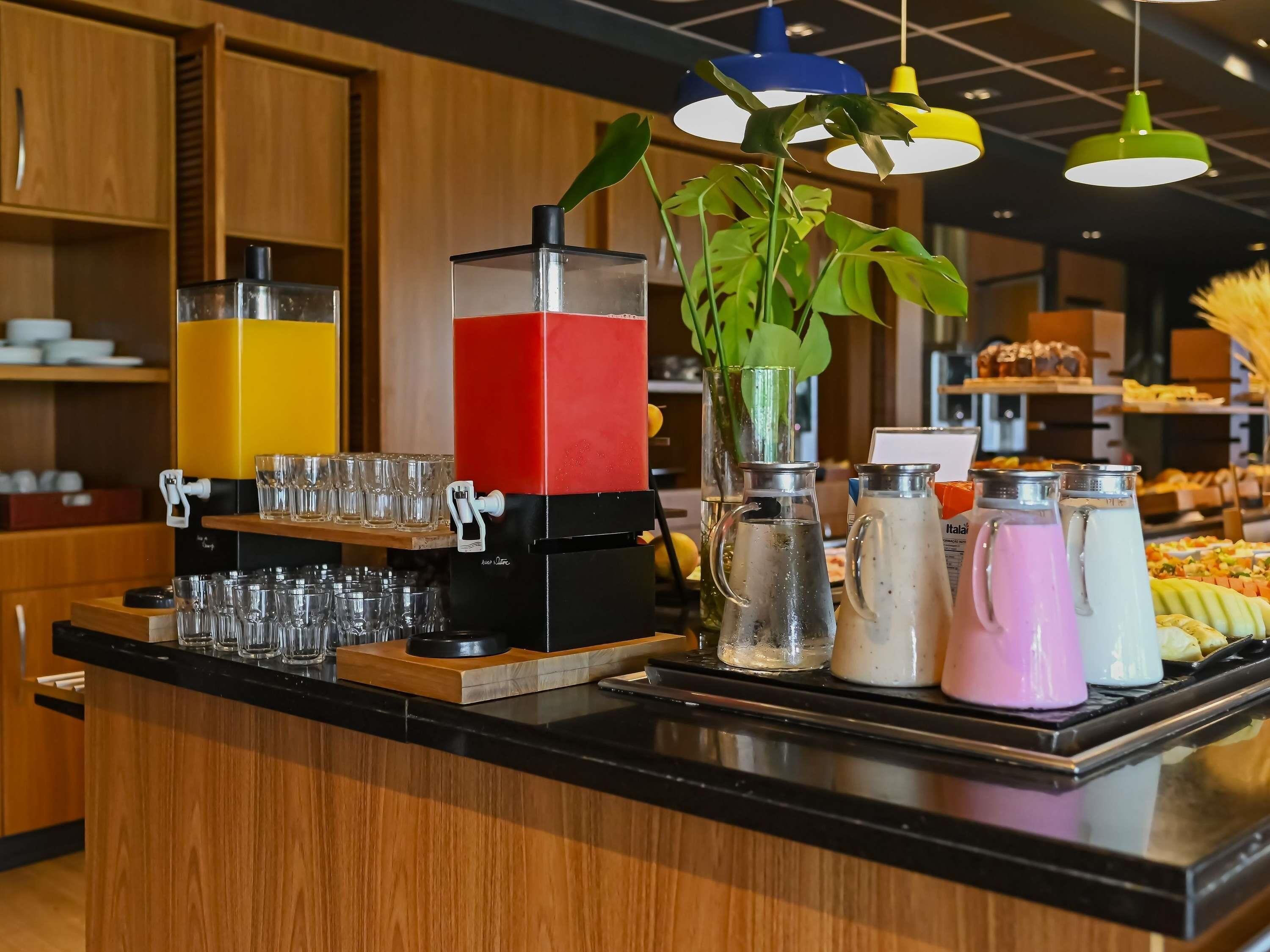 A buffet counter with a juice dispenser, a pitcher, and a variety of food items.