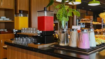A buffet counter with a juice dispenser, a pitcher, and a variety of food items.