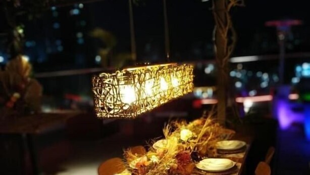A long dining table set for a meal with a decorative centerpiece, chairs, and a hanging light fixture. - Ibis Jundiai Shopping (Jundiai)