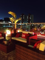 A rooftop lounge area with seating and a potted plant.