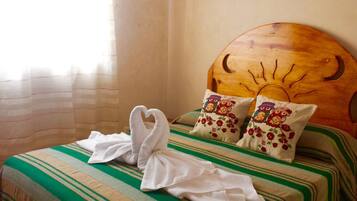 A bed with a striped green and beige bedspread, two pillows with owl designs, and two towels folded on the bed.