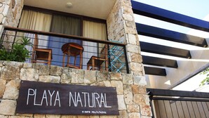 Un edificio de piedra con un letrero que dice "PLAYA NATURAL" y un número de contacto.