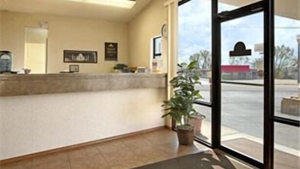 A reception area with a counter, a potted plant, and a view of the street through large windows.