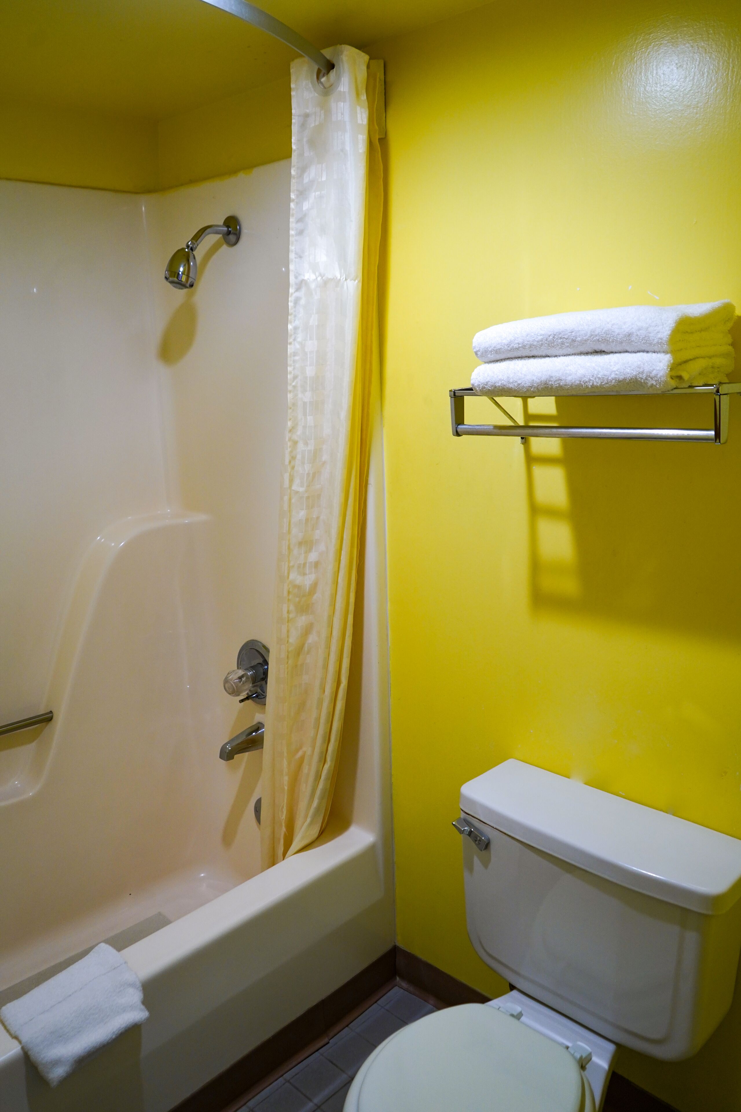 Un baño con bañera, inodoro y un estante con toallas.