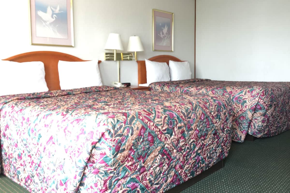 Une chambre d’hôtel avec un grand lit, deux lampes de chevet et deux tableaux encadrés au mur.