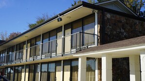 A two-story building with a balcony, large windows, and a stone facade.