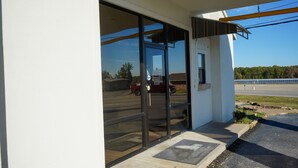 A building entrance with a glass door, a concrete step, and a small planter.