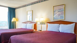 A hotel room with two beds, each with a wooden headboard, a nightstand with a lamp, and a painting on the wall.