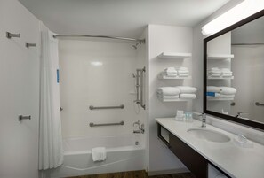 Un baño moderno con bañera, ducha y lavabo. Hay toalleros y un espejo sobre el lavabo.