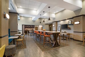 Ein modernes Restaurant mit Barbereich, verschiedenen Sitzmöglichkeiten und einer Decke mit eingelassener Beleuchtung.