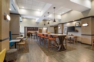 Un restaurante moderno con barra, distintas opciones de asientos e iluminación empotrada en el techo.
