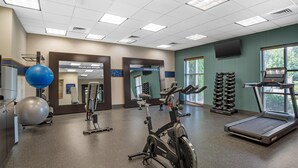 A gym with exercise equipment, a mirrored wall, and a window with blinds. - Hampton Inn & Suites Fort Mill (Fort Mill)