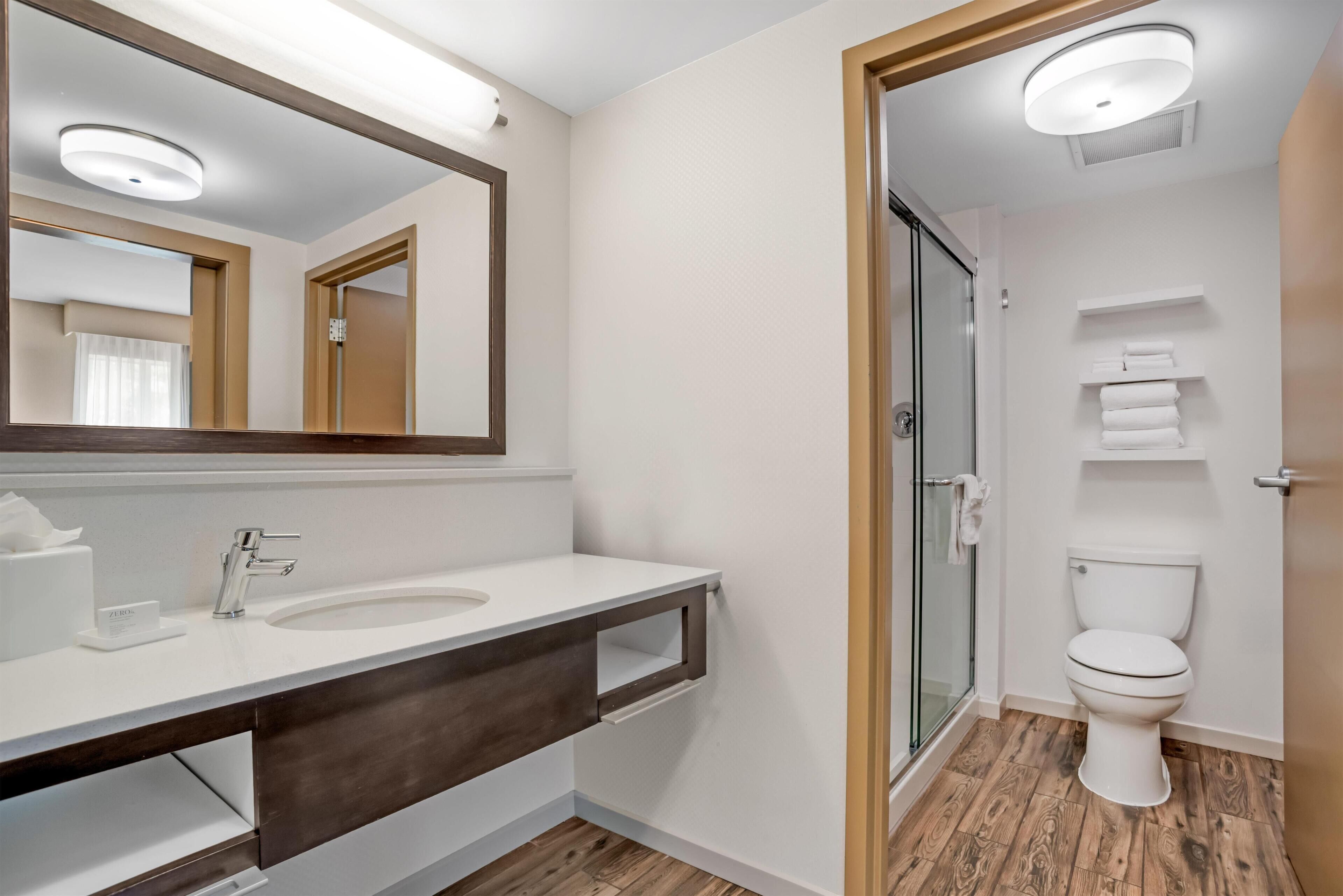 A modern bathroom with a large mirror, a sink, and a toilet.
