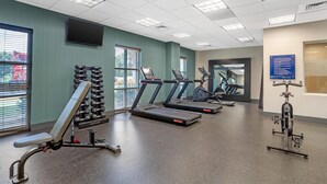 A gym with treadmills, dumbbells, and exercise equipment.