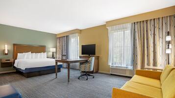 Une chambre d’hôtel avec un lit, un bureau, une télévision et un canapé.