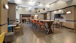 A modern restaurant with a bar area, multiple seating options, and a ceiling with recessed lighting.