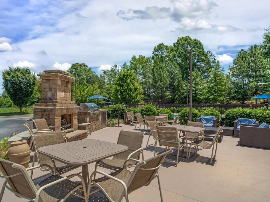 An outdoor patio with stone barbecue, seating, and greenery.