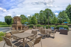 An outdoor patio with stone barbecue, seating, and greenery.