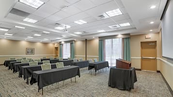 A conference room with tables, chairs, a podium, and a carpeted floor.