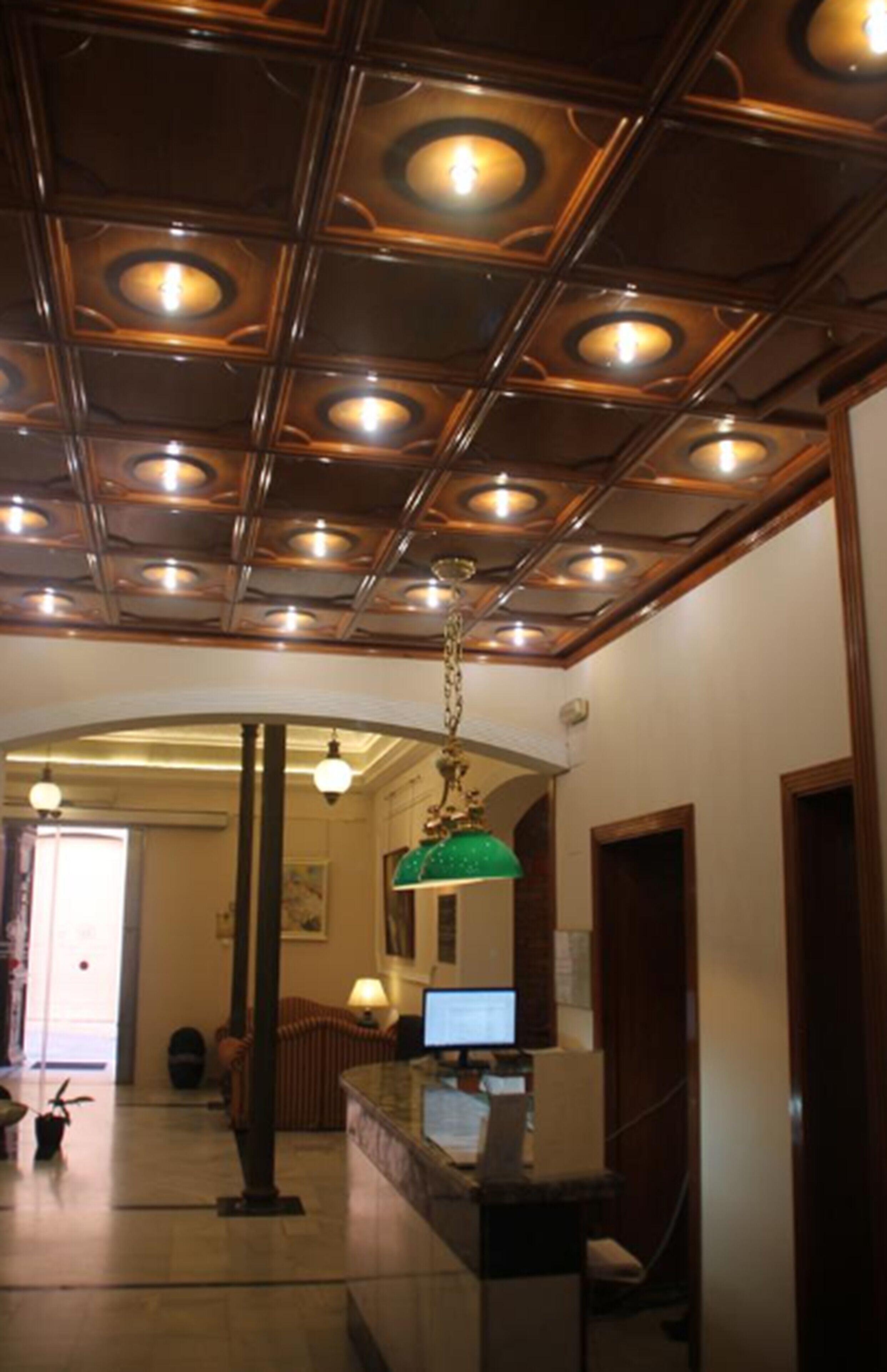 Un vestíbulo con techo de madera, un mostrador de recepción y una lámpara verde.
