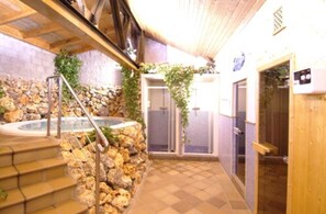 A stone wall with a hot tub, a wooden staircase, and a wooden door. - Hotel Palacio de Oñate Spa (Guadix)