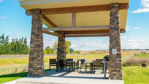 A covered outdoor seating area with stone pillars, tables, and chairs.