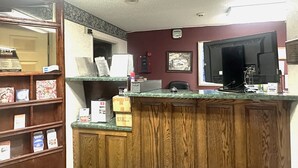 A reception area with a wooden counter, a computer, and a large monitor.