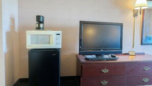 A hotel room with a microwave, a television, and a small refrigerator.