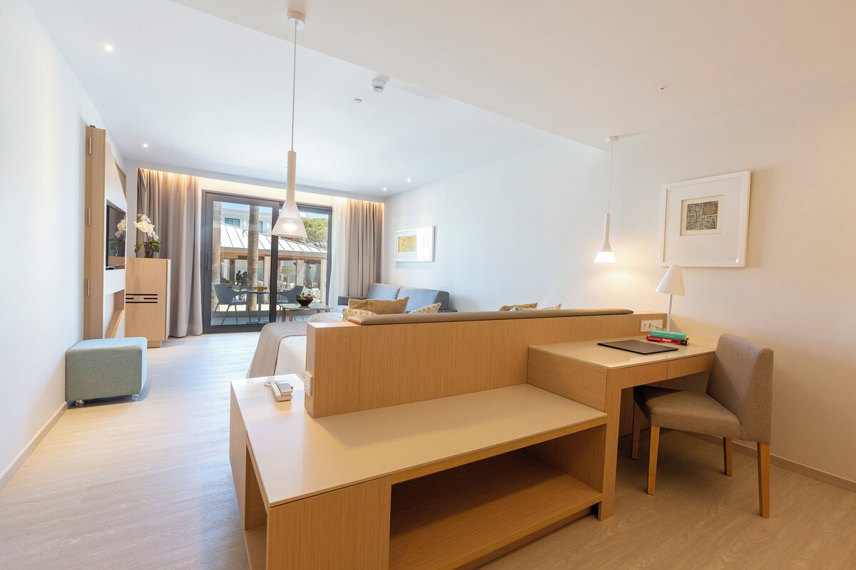A modern hotel room with a sofa, a desk, a chair, and a small table.