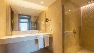 Un baño moderno con ducha de vidrio, un espejo grande y un tocador doble.