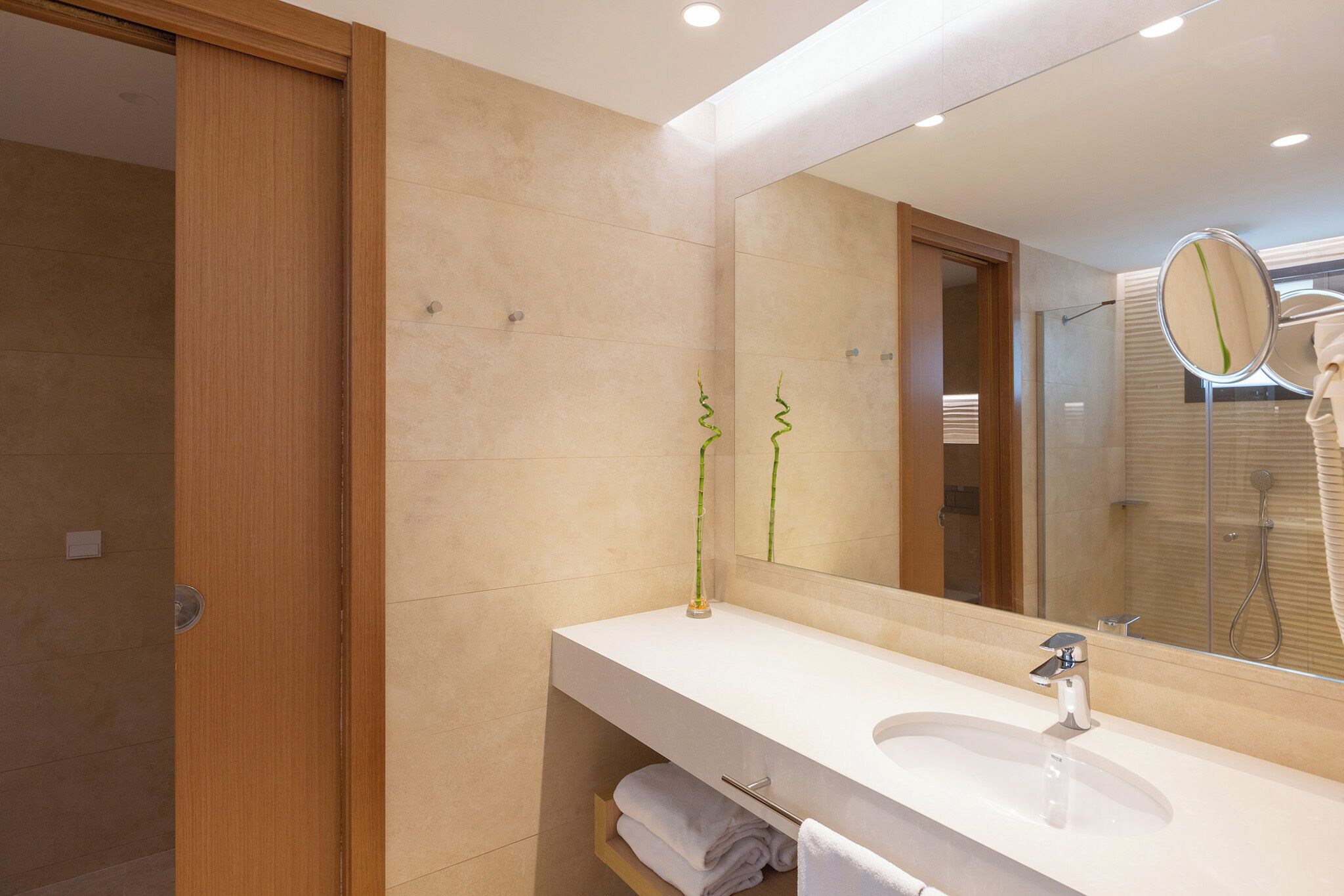 Un baño moderno con un espejo grande, dos lavamanos y una ducha.