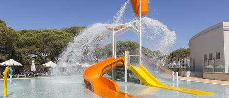 A water park with two slides, a pool, and umbrellas.