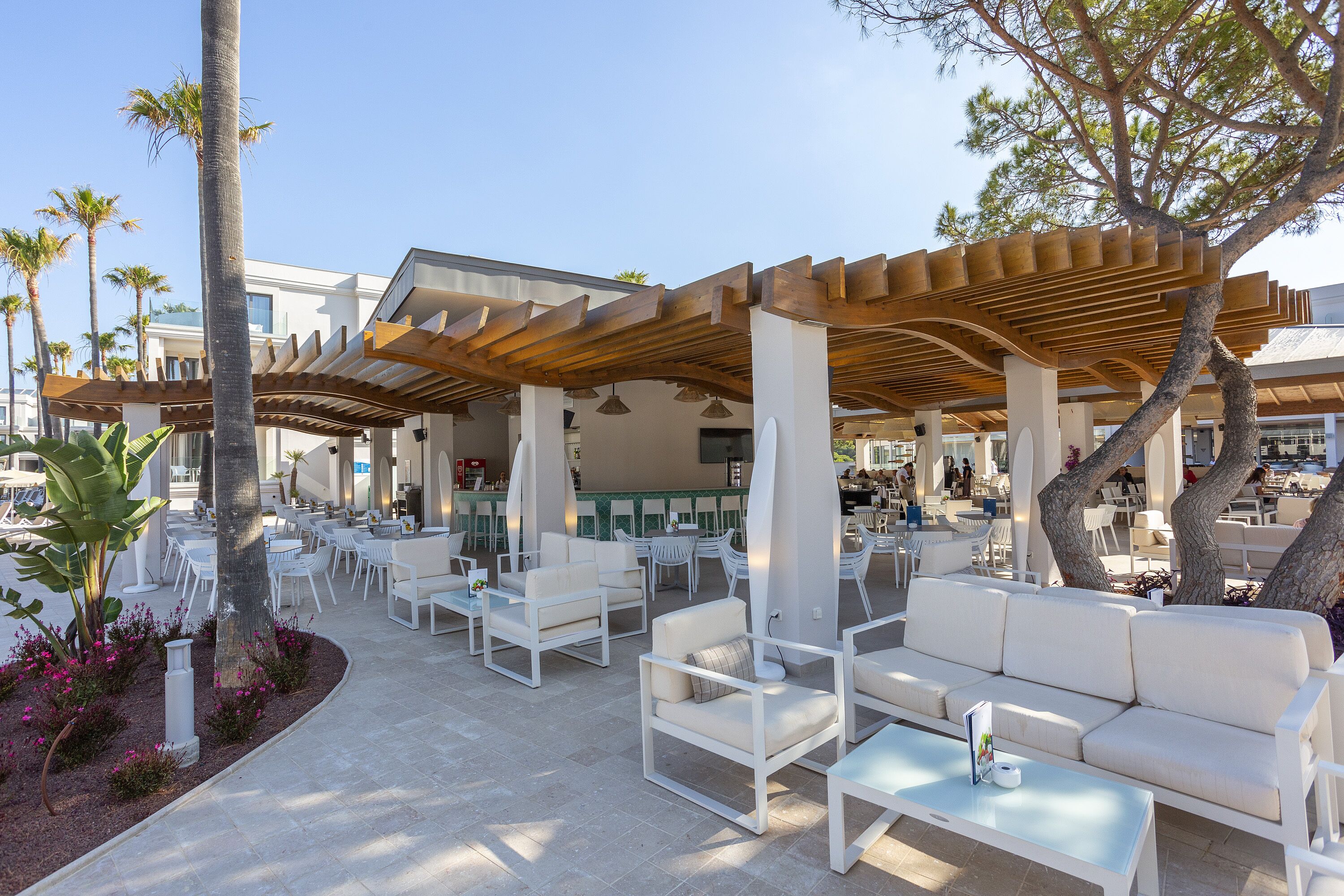 An outdoor seating area with white furniture and a wooden pergola.