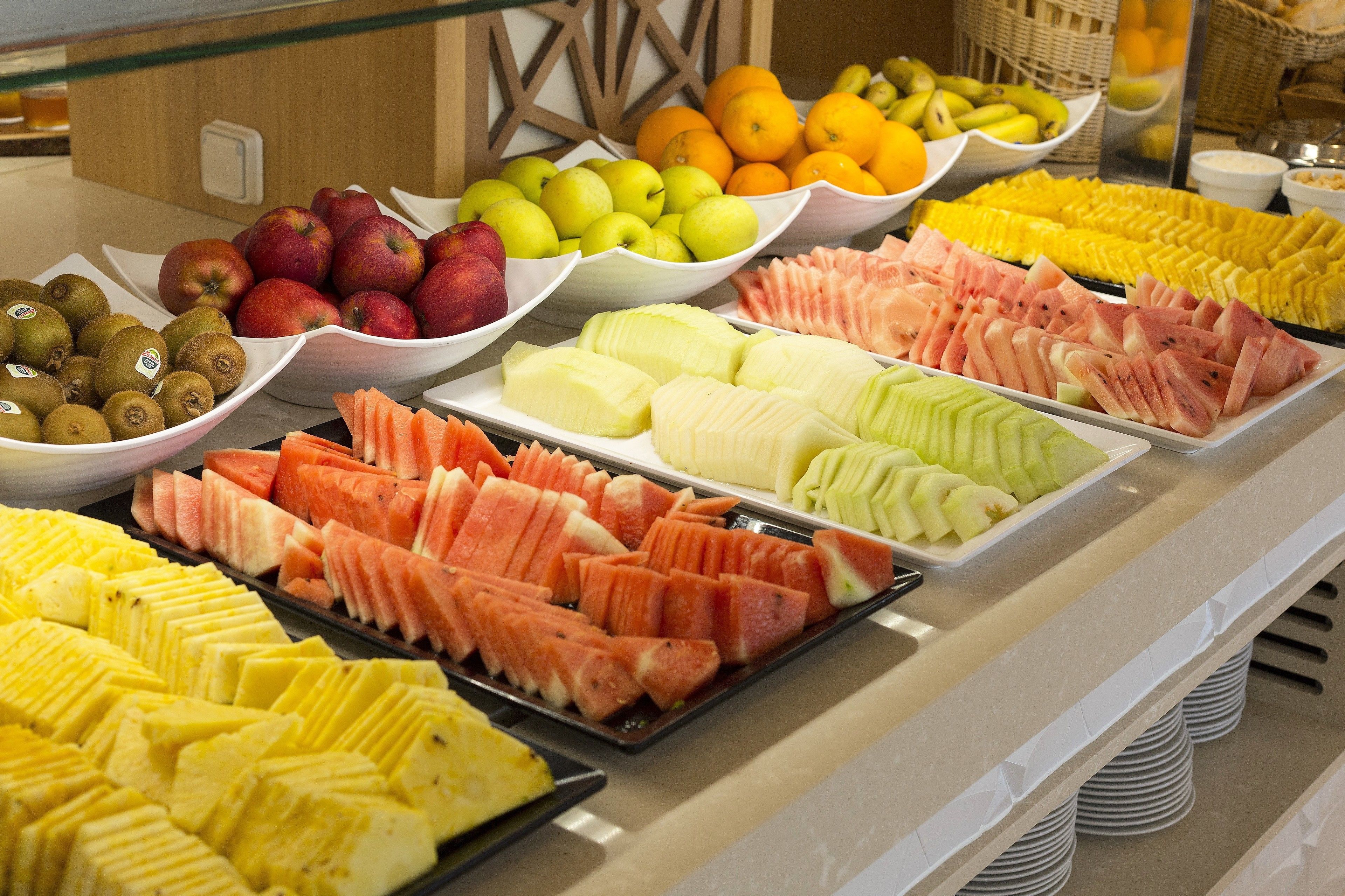 A buffet with various fruits and vegetables, including apples, oranges, and watermelon.
