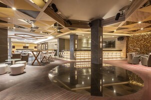 A modern lobby with a central reflective floor, seating areas, and a reception desk.